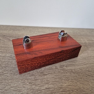May include: A wooden stand with two silver metal holders. The stand is a rich reddish-brown colour and has a smooth, polished finish.