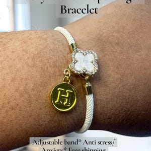 以下が含まれることがあります： 白いロープブレスレット。 金色のクローバーチャームと、文字「H」が入った金色の丸いチャームが付いています。 クローバーチャームには、小さな透明なクリスタルがちりばめられています。 このブレスレットは、フィジェットおもちゃとして設計されています。