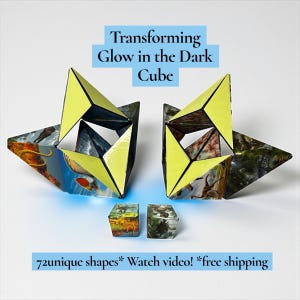 以下が含まれることがあります： 黄色と黒の三角形のパネルを備えた、2つの開いた構成の、暗闇で光る変形キューブ。 キューブはカラフルな画像で装飾されています。 2つの小さなキューブが一番下にあります。 テキストは「Transforming Glow in the Dark Cube」と表示されています。
