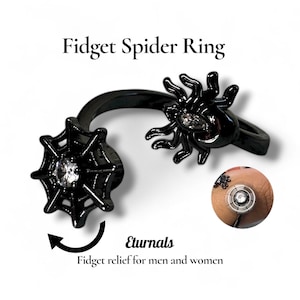 May include: A black fidget spider ring with a spider and web design. The ring features a spider with a gem in the center and a web with a gem in the center. The text "Fidget Spider Ring" is at the top.
