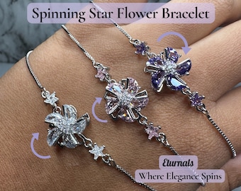 May include: Three silver bracelets with spinning flower and star charms. The bracelets feature clear, pink, and purple flower designs with sparkling accents. The text "Spinning Star Flower Bracelet" is visible.