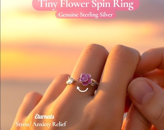 May include: A sterling silver Tiny Flower Spin Ring with a pink flower design. The ring is shown on a person's finger, with the flower element spinning. The text "Stress/ Anxiety Relief" is also visible.