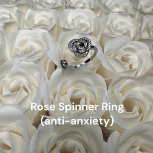 May include: A silver rose spinner ring with clear cubic zirconia stones. The ring is designed to spin and is marketed as an anti-anxiety tool.  Rose Spinner Ring (anti-anxiety)