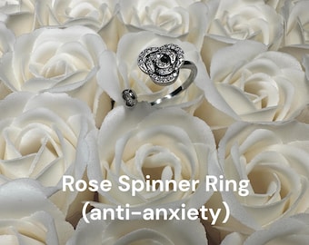 May include: A silver rose spinner ring with clear cubic zirconia stones. The ring is designed to spin and is marketed as an anti-anxiety tool.  Rose Spinner Ring (anti-anxiety)