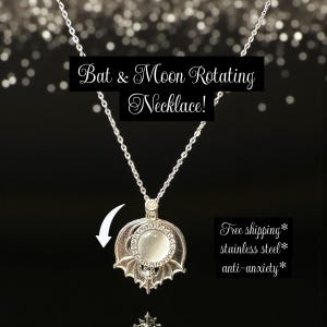 May include: A silver necklace with a pendant showing a bat and moon design. The pendant has a circular stone and is suspended from a fine chain. The text "Bat & Moon Rotating Necklace!" is displayed against a dark backdrop.
