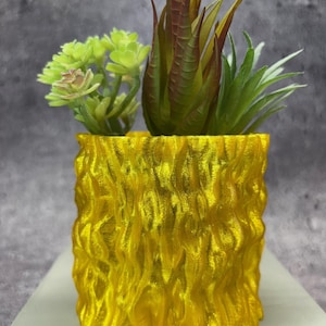 May include: A yellow, textured ceramic planter with a wood-like finish. The planter is filled with artificial succulents.