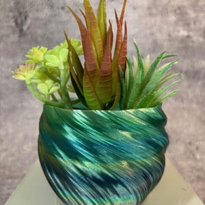 May include: A green and blue swirl planter with a variety of succulents. The planter is made of a smooth, shiny material and has a unique, modern design.