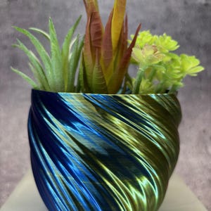 May include: A blue and green swirl planter with a variety of succulents. The planter is made of a smooth, shiny material.