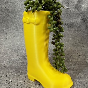 May include: A yellow rubber boot planter with a green succulent plant growing out of it.