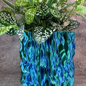 May include: A green and blue patterned ceramic planter with a leafy green plant inside.