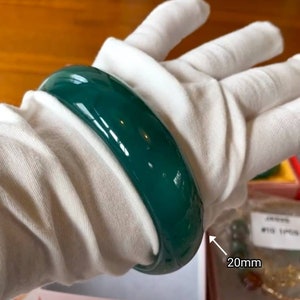 May include: A green jade bangle bracelet with a glossy finish. The bracelet is 20mm wide.