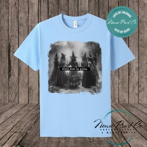Witches in the forest design on custom t-shirt with the slogan “Girls Will Be Girls”. Feminist and empowering print on 100% cotton tee, perfect for girls and women, printed using high-quality DTF/DTG technology.
