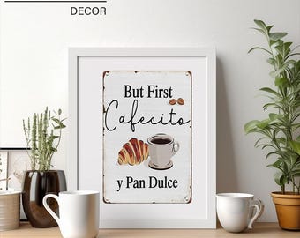 May include: Framed wall art with the text "But First Cafecito y Pan Dulce" featuring a croissant and coffee cup illustration. The art is displayed on a wooden surface with two white mugs and potted plants.