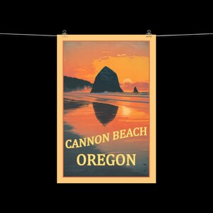 May include: A framed poster depicting Cannon Beach, Oregon, at sunset. The image shows a large rock formation in the ocean, reflected in the wet sand. The sky is a gradient of orange and yellow, with the text "CANNON BEACH OREGON" at the bottom.