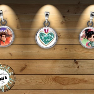 May include: Three silver charm pendants with glass inserts. The first pendant features a cartoon character with a red shirt and blue jeans. The second pendant features a green heart-shaped cookie with the text "You're My Hero". The third pendant features a cartoon character with a green shirt and black hair.