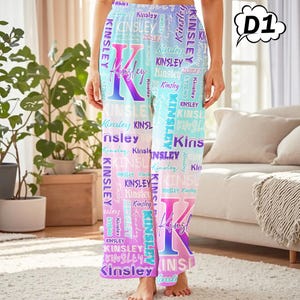 May include: Light blue, pink, and purple pajama pants with the name "Kinsley" printed repeatedly in a script font. A large letter "K" is centered on the pants. The pants are made of a soft material.