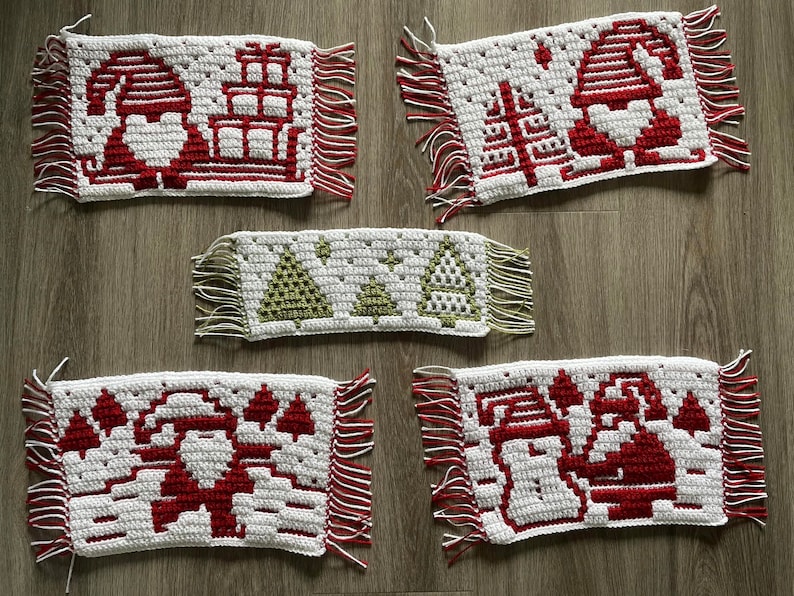 Pu&ograve; includere: Cinque tovagliette natalizie all'uncinetto fatte a mano. Ogni tovaglietta bianca presenta un diverso design festivo rosso e bianco, tra cui Babbo Natale, alberi di Natale e regali. I bordi sono rifiniti con frange rosse e bianche.