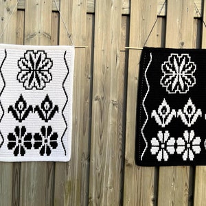 Può includere: Due arazzi da parete in crochet bianco e nero con motivi floreali geometrici. Gli arazzi sono realizzati con filato bianco su sfondo nero e filato nero su sfondo bianco.