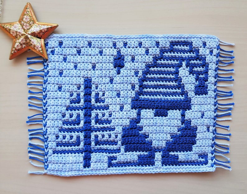 Pu&ograve; includere: Un sottopentola all'uncinetto fatto a mano, nei toni del blu e del bianco, con un motivo geometrico e bordi sfrangiati. Il sottopentola quadrato presenta un design dettagliato. &Egrave; un oggetto decorativo.