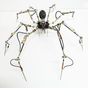 Puede incluir: Una escultura de araña de estilo steampunk hecha de metal, con un cuerpo negro y plateado y detalles dorados. La araña tiene ocho patas, cada una con múltiples articulaciones y detalles.