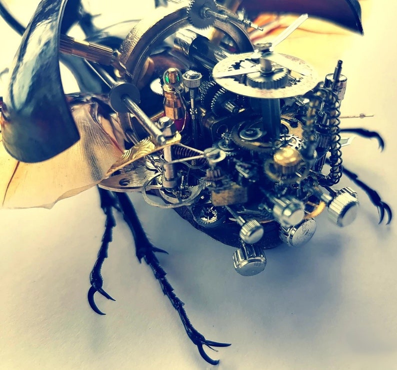 May include: A detailed steampunk-style sculpture of a beetle with intricate gears and clockwork mechanisms. The sculpture is made of metal and has a dark brown and gold finish.