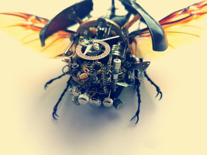 May include: A steampunk-style beetle made of metal gears and clock parts. The beetle has wings and legs, and its body is covered in intricate details.