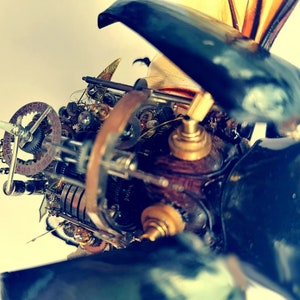 May include: A close-up of a steampunk-style insect sculpture with intricate gears and mechanisms. The sculpture is made of metal and has a dark blue and brown color scheme.