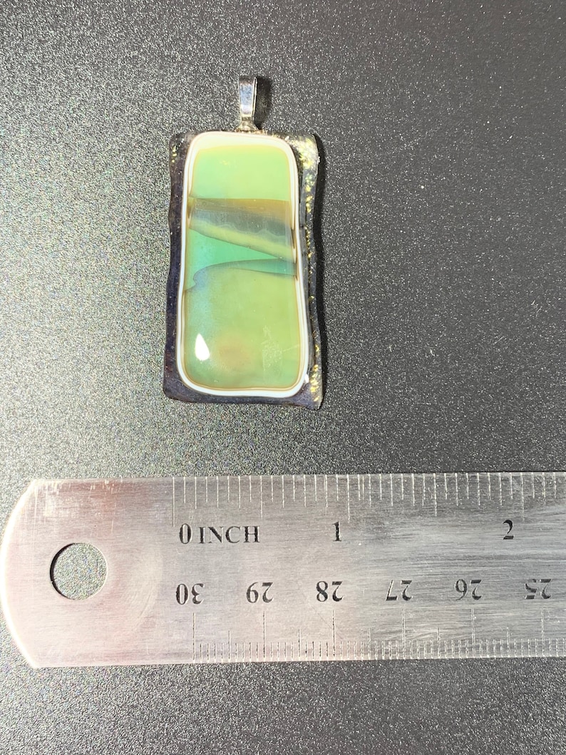 Glass fused pendant that has a landscape lake setting image.