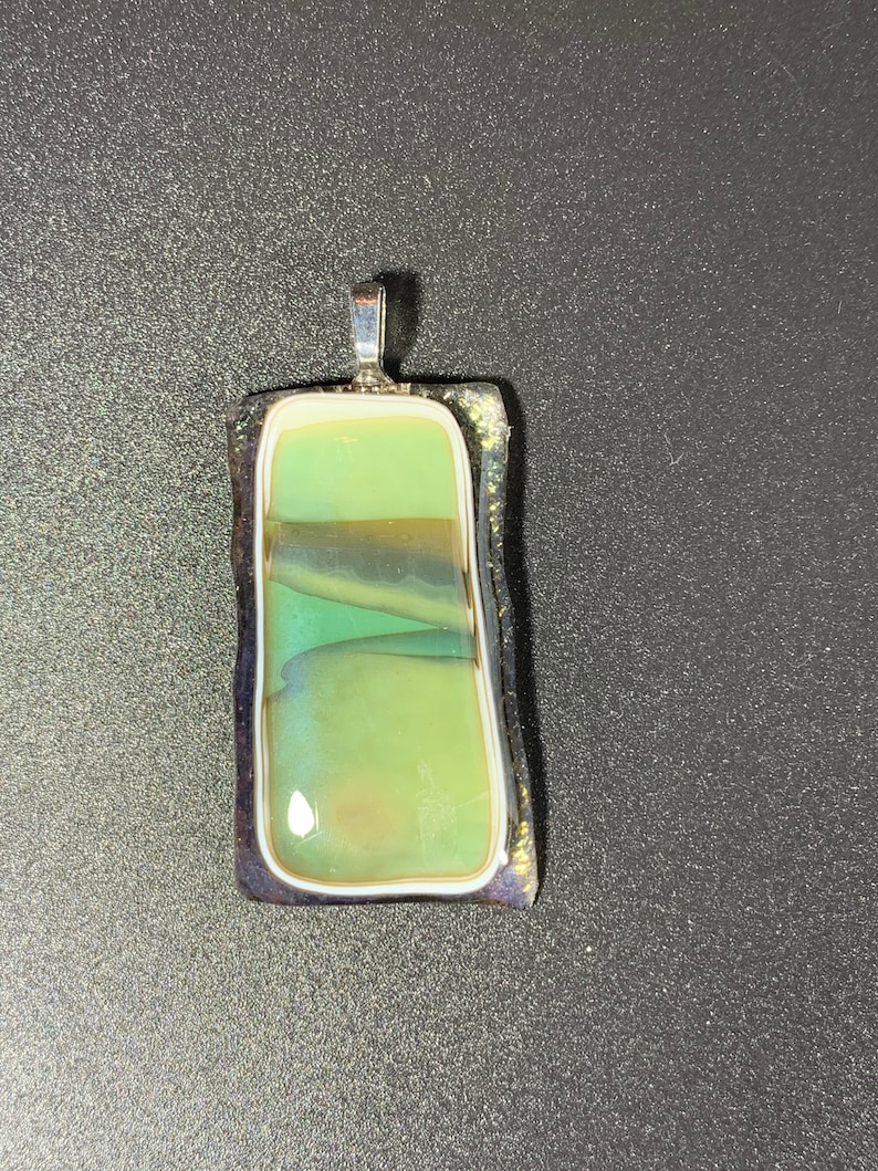 Glass fused pendant that has a landscape lake setting image.