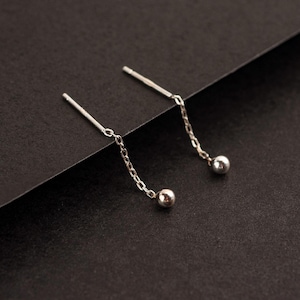May include: A pair of silver dangle earrings with small round beads at the end of the chains.
