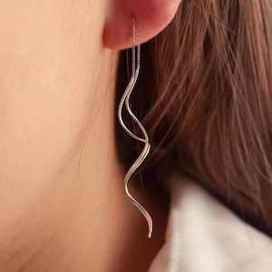 May include: Silver dangle earrings with a twisted, wavy design.