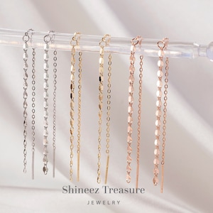May include: A set of eight long, delicate chain earrings in silver, gold, and rose gold. The chains are made of small, oval-shaped links. The earrings are displayed on a white background.