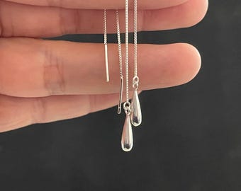 Può includere: Un paio di orecchini a goccia d'argento con catene delicate.