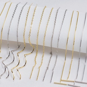 May include: A set of 10 pairs of gold and silver chain earrings with different charms, including stars, wavy lines, and straight bars.