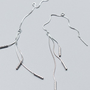 May include: A pair of silver dangle earrings with multiple chains and textured bar accents.