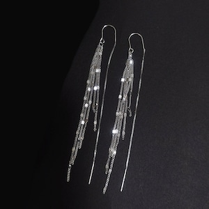 May include: A pair of silver dangle earrings with multiple chains and square-shaped beads. The earrings are long and delicate.
