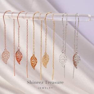 May include: A set of six delicate gold, rose gold, and silver chain earrings with leaf-shaped charms. The earrings are displayed on a white background.