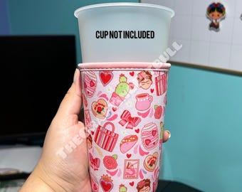 May include: Pink and white insulated cup sleeve with a colorful pattern of Mexican-inspired designs, including hearts, flowers, cacti, and a Frida Kahlo portrait. The text "CUP NOT INCLUDED" is printed on the sleeve.