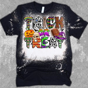 May include: A black t-shirt with a white bleach design featuring the text "Trick or Treat" in colorful patterned letters. The design also includes a pumpkin, skull, witch's hat, and a book.