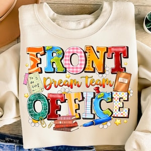 以下が含まれることがあります： クリーム色のスウェットシャツ。カラフルなグラフィックで「FRONT Dream Team OFFICE」と書かれています。デザインには地球儀、本、ペン、To-Doリストが含まれており、すべて遊び心のある漫画スタイルです。カジュアルで快適な衣服です。