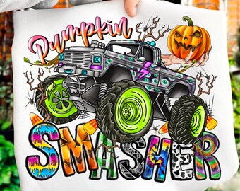 May include: White graphic tee featuring a monster truck with neon green wheels, a jack-o'-lantern, and the text "Pumpkin Smasher" in colorful letters. The design has a Halloween theme with spiderwebs and candy corn.