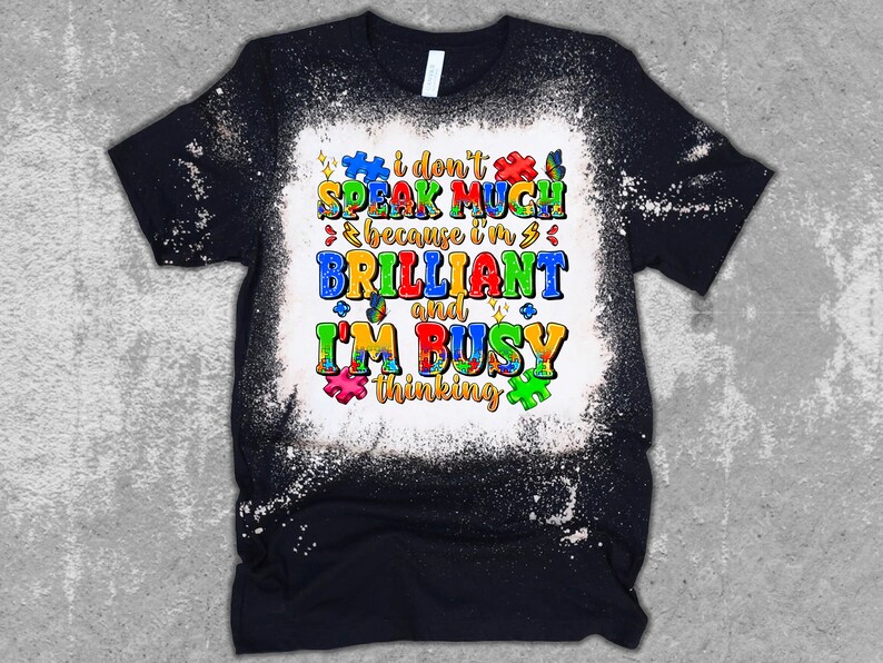 May include: Black t-shirt with a white bleach design. The design features a colorful puzzle piece pattern and the text "I don't speak much because I'm brilliant and I'm busy thinking."