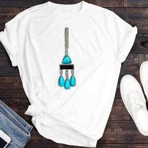 May include: White t-shirt featuring a turquoise blue gemstone pendant necklace design. The necklace has a large triangular gemstone with smaller teardrop-shaped gemstones hanging from it.