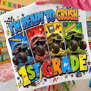 May include: A white fabric print featuring the text I'M READY TO CRUSH 1ST GRADE. The design includes four vertical panels with monster trucks, a pencil, an apple, a notebook, a ruler, and a backpack, decorated with stars and A+ symbols.
