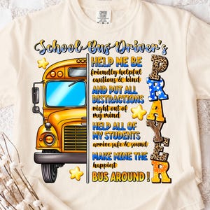 May include: Cream-colored t-shirt with a graphic featuring a yellow school bus and the words "School Bus Driver's Prayer." The design includes text such as "Help Me Be" and "Make Mine The Happiest Bus Around!" with star accents.