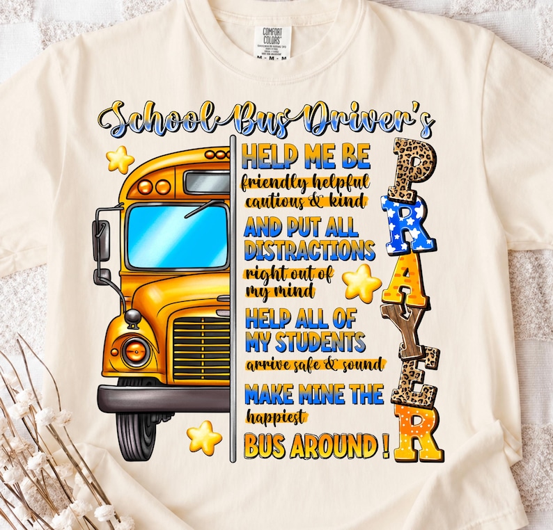 May include: Cream-colored t-shirt with a graphic featuring a yellow school bus and the words "School Bus Driver's Prayer." The design includes text such as "Help Me Be" and "Make Mine The Happiest Bus Around!" with star accents.