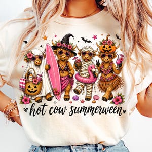 May include: A cream-colored t-shirt featuring a graphic of four Highland cows dressed in Halloween-themed summer attire, including a ghost, a witch, a mummy, and a pumpkin head. The text below the cows reads "hot cow summerween".