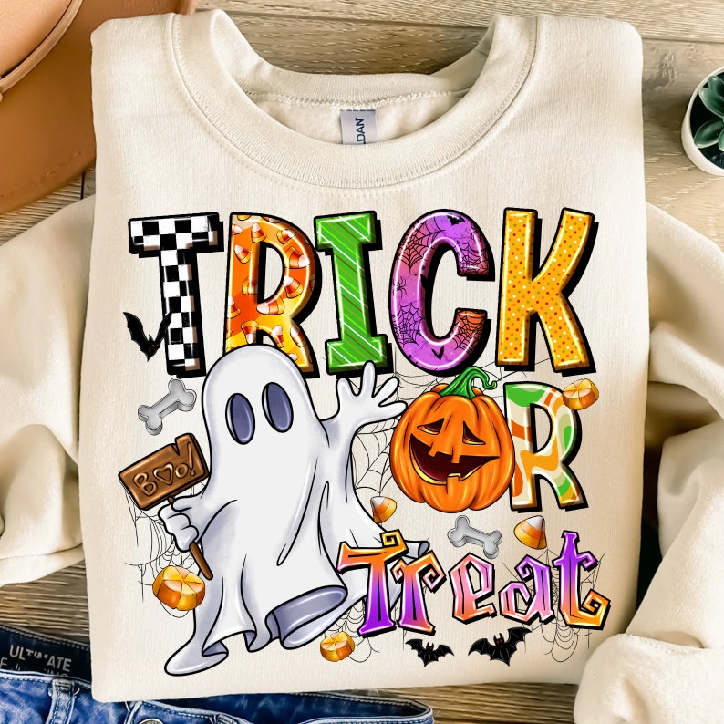 May include: A cream-coloured sweatshirt with a colourful "Trick or Treat" graphic. The graphic features a ghost, a pumpkin, candy corn, and bats.