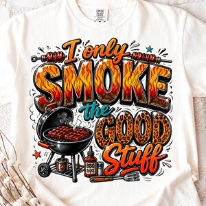 Può includere: Una t-shirt bianca con una stampa grafica che riporta il testo I only SMOKE the GOOD Stuff. Il design include un barbecue a carbone nero con bistecche, una bottiglia di salsa barbecue, una saliera, un forchettone e spiedini colorati.