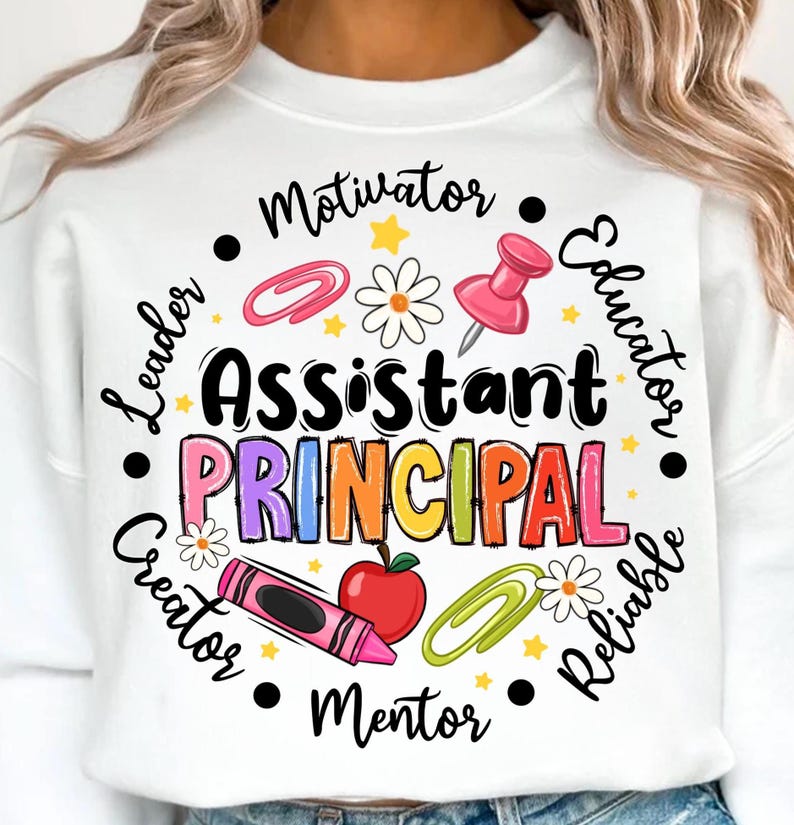 May include: White sweatshirt with the words "Assistant Principal" in colorful letters, surrounded by school-themed graphics like a pushpin, apple, and crayon. The words "Leader," "Educator," "Motivator," and other positive attributes encircle the main text.